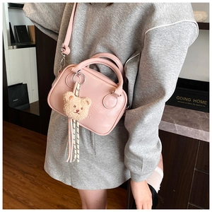 Detail of pink mini pillow bag with cute bear charm and embossed lettering on smooth PU leather