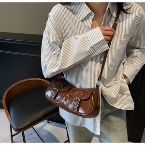 Detail of a brown faux leather underarm bag with decorative silver buckle pockets