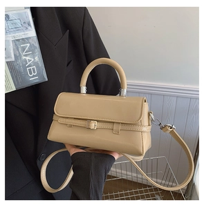 Detail of minimalist beige square handbag with glossy finish and silver buckle hardware