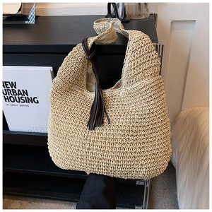 Close-up of beige woven tote bag with fringe detail and natural texture