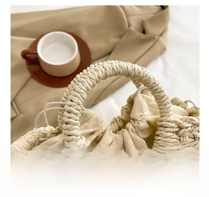 Detailed macro view of the sturdy woven handles and fabric drawstring liner on the straw bag