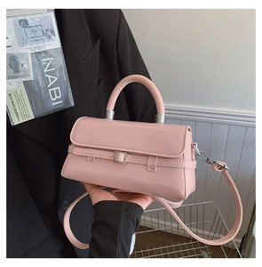 Detail of pink faux leather handbag featuring silver metal buckle and top handle