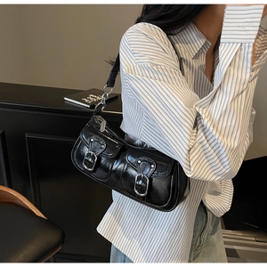Detail of glossy black patent leather underarm bag with silver buckle pockets