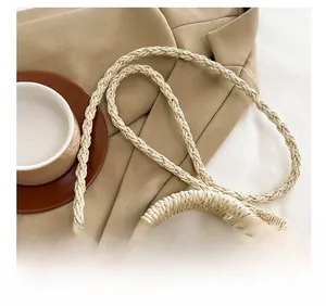 Detail showing the braided shoulder strap and woven ring handle of this cream straw bag