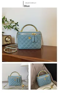 Close-up of blue quilted bucket bag with gold flower logo and metal handle