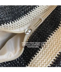 Detailed macro view of the smooth silver metal zipper on a woven black and white tote bag