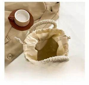Detail view of woven straw bucket bag with drawstring liner beside a coffee cup
