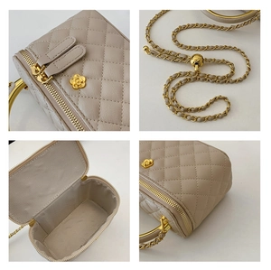 Detail of beige quilted box bag showing golden camellia hardware and metal chain strap