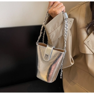 Close-up of a silver mirror-finish bucket bag with a chunky metal chain handle