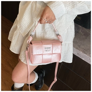 Detail of pink woven handbag featuring pearl strap and silver metal brand logo