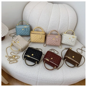 Quilted bucket bags with chain straps in seven colors displayed on a white stool