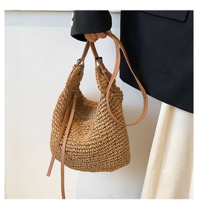 Detail of woven straw tote bag texture with brown leather strap and metal buckle
