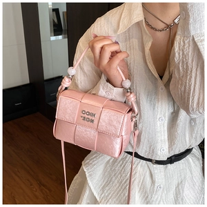 Detail of pink woven leather handbag featuring luxury beaded handle and silver logo