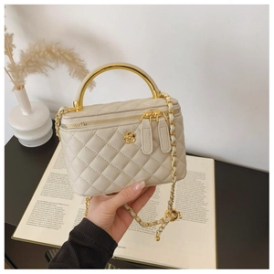 Detail of cream quilted leather box bag with golden metal handle and flower ornament