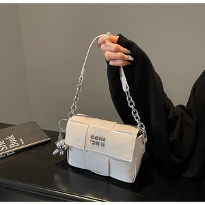 Détail du sac carré tressé blanc avec pendentif lapin argenté et bandoulière chaîne
