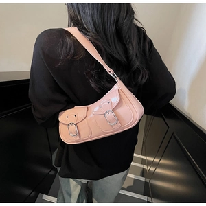 Detailed macro view of trendy pink patent leather shoulder bag with metallic buckles