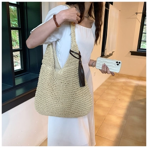 Detail of woven straw hobo bag showing beige texture and dark brown tassel charm