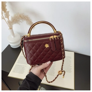 Macro detail of wine red quilted leather box bag with gold floral logo and chain strap