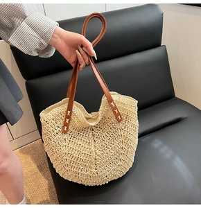 Detail of hand-woven straw tote with brown leather handles and X-stitch reinforcement