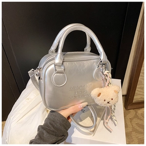 Detail of silver metallic pillow bag with embossed logo and cute plush bear charm