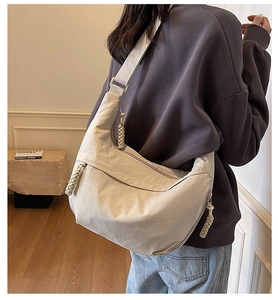Detail of beige crescent bag featuring large capacity and unique braided knot zipper pull