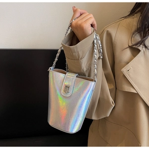 Chic laser iridescent bucket bag with silver chain worn by a model in a beige coat