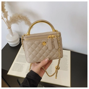 Detail of beige quilted vanity bag with gold camellia clasp and metal chain strap