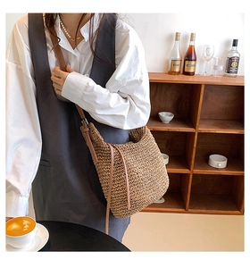 Detail of hand-woven straw shoulder bag with leather strap and decorative drawstring