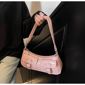 Detail view of pink glossy faux leather baguette bag with metal buckle pockets
