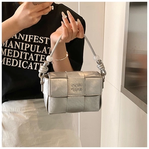 Detailed view of silver woven square handbag featuring pearl and metal bead handle