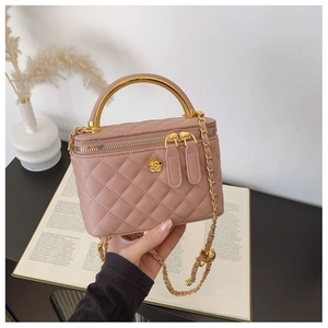 Pink quilted box bag with a gold metal handle and floral clasp detail in a lifestyle setting
