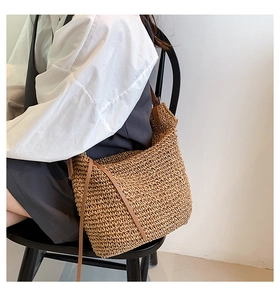 Detail of hand-crocheted straw tote bag texture with brown leather shoulder strap