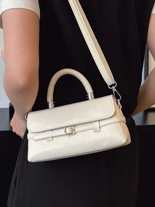 Minimalist cream white crossbody bag with top handle and metal buckle shown on person