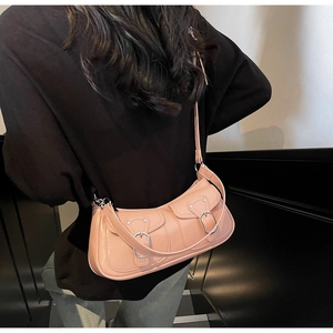 Detail of a peach crescent underarm bag with double metal buckles on a black outfit