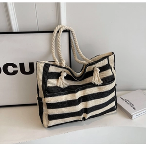 Detail of the woven texture and cream cotton rope handles on a striped tote bag