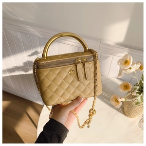 Close-up of khaki quilted vanity bag featuring gold metal handle and flower detail