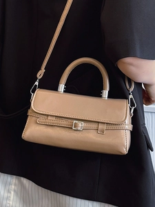 Minimalist beige square handbag with top handle and crossbody strap on black blazer