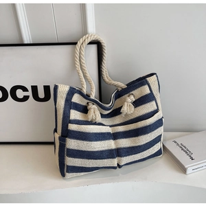 Detail of nautical navy blue striped woven tote bag with rope handle and fringe accent