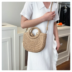 Detail of hand-woven straw crossbody bag with circular handles and drawstring liner