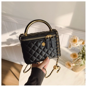 Detail of black quilted leather box bag with gold camellia hardware and chain strap