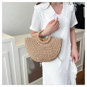 Detail of hand-woven straw handbag featuring a semi-circular design and satin drawstring lining