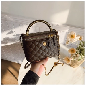 Detailed close-up of brown quilted leather vanity box bag with golden camellia flower charm