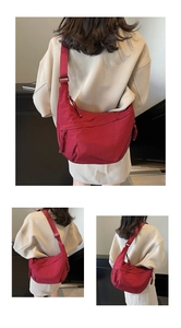 Detail of red nylon dumpling crossbody bag featuring woven zipper knot and wide strap