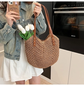 Close-up of brown straw woven tote bag featuring durable PU leather shoulder straps