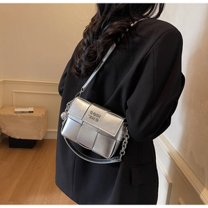 Détail d'un sac bandoulière argenté tissé avec bandoulière chaîne et pendentif sphérique
