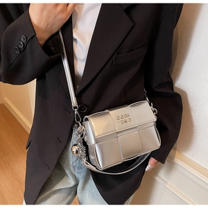 Détail du sac bandoulière tressé argenté avec chaîne en métal et breloque sphère