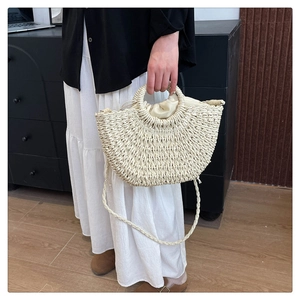 Detail of hand-woven straw bag featuring round top handle and secure drawstring liner