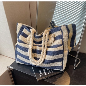 Detail of blue and white striped woven tote bag with rope handles in a mirrored setting