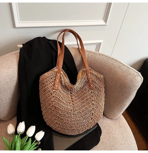 Macro shot of hand-woven straw texture and dark brown leather handle on tote bag