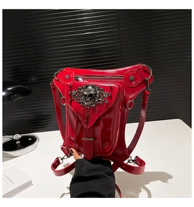 Detalle de riñonera punk de charol rojo con emblemas de calaveras plateadas y tachuelas
